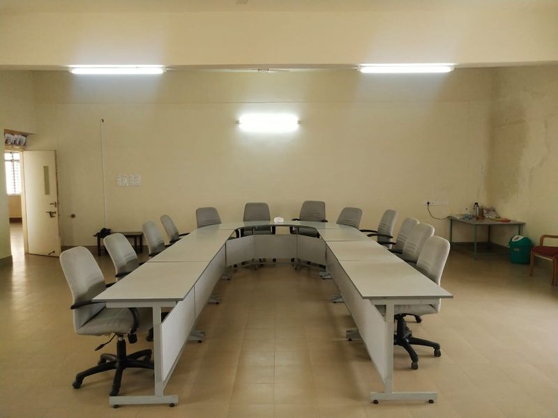 The conference room, a single meeting table with seating around it